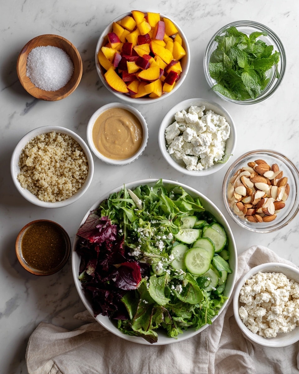 The image shows a white bowl filled with mixed greens that include different shades of green and some reddish-purple leaves as the main layer in the center. Around the bowl, there are smaller white bowls and containers with various ingredients: bright green chopped mint and basil leaves at the top, orange and red diced peaches next to the white balsamic in a clear glass bowl, light tan tahini in a white bowl, crumbled white goat cheese in a small clear bowl, a bowl of cooked light beige quinoa, sliced green cucumbers, chopped almonds below, and garlic powder in a small bowl. There is a wooden small bowl with white powder, likely salt, in the top left. The whole setup is on a white marbled texture with a light beige cloth nearby. photo taken with an iphone --ar 4:5 --v 7