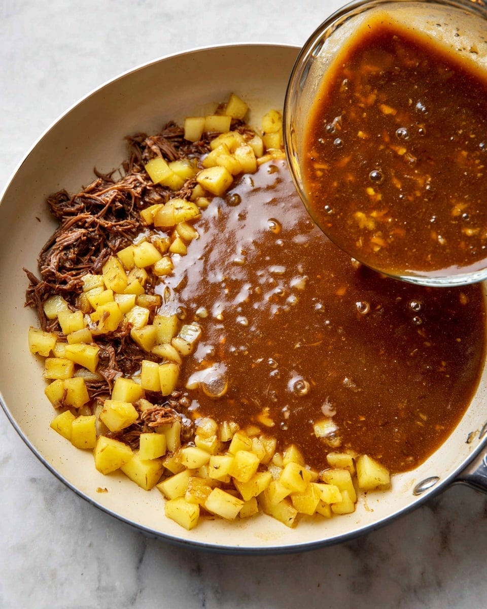 In a white frying pan, there is a mix of cooked diced yellow potatoes and shredded dark brown meat along the edges. A rich, thick brown sauce with visible pieces of small white ingredients is being poured from a clear glass bowl into the middle of the pan, covering part of the potatoes and meat. The pan sits on a white marbled surface, and the sauce has a glossy, smooth texture with small bubbles on the surface. photo taken with an iphone --ar 4:5 --v 7