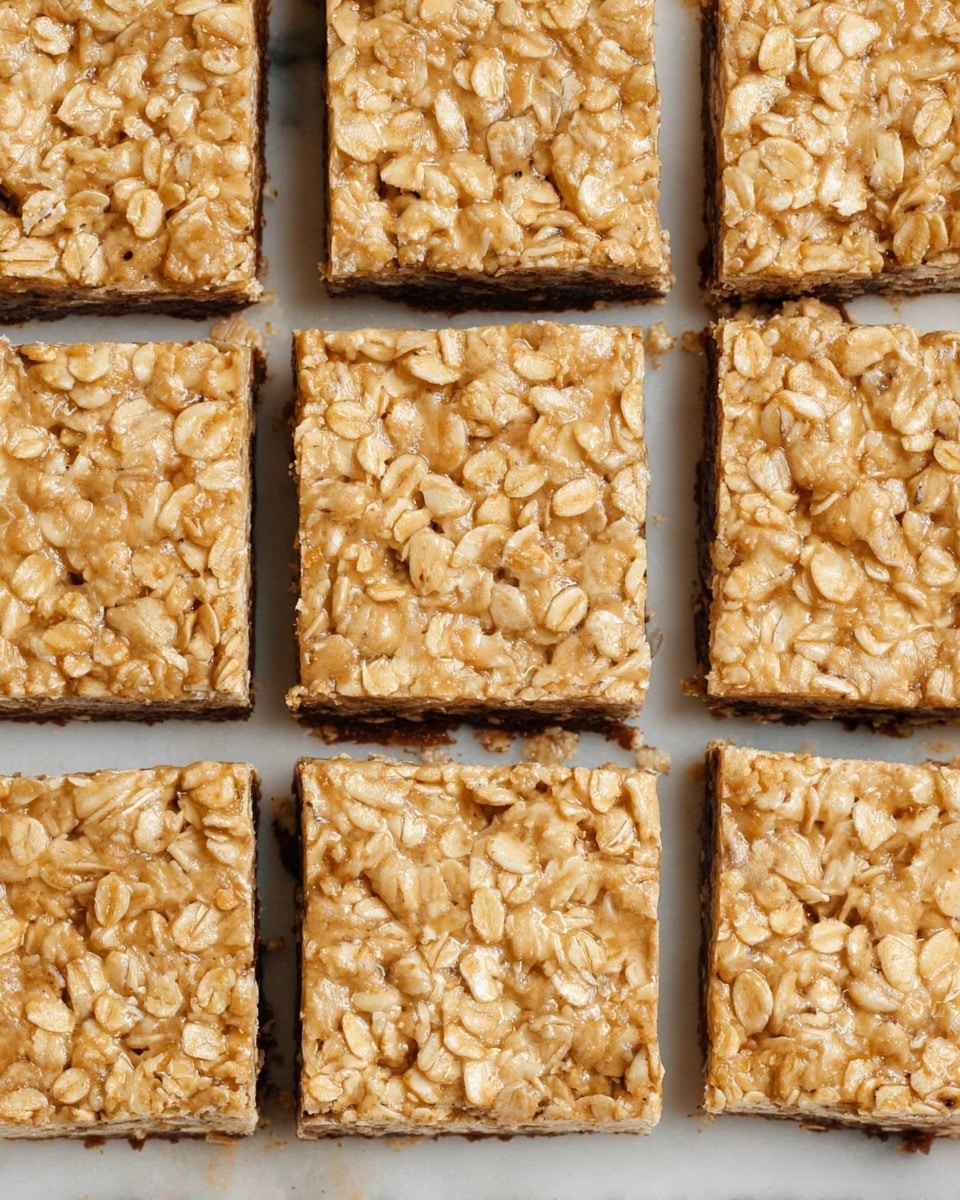 The image shows 12 oat bars arranged in a 3 by 4 grid on a white marbled surface. Each bar is square-shaped with a light tan color, packed with visible oat flakes giving a textured and slightly uneven surface. The bars are neatly separated from each other by thin lines, showing clear edges and a firm consistency. The oat flakes create a rough pattern across the top that looks dry but compact. photo taken with an iphone --ar 4:5 --v 7