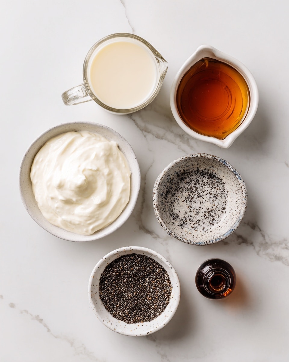 The image shows five containers placed on a white marbled surface, each holding different ingredients. At the bottom left is a white bowl filled with smooth, thick plain yogurt. Above it to the left is a small clear glass pitcher containing creamy almond milk. To the right of that is a small white pitcher with a speckled edge, holding dark amber maple syrup. Above the syrup, near the top center, is a white bowl filled with tiny black and white chia seeds with a rough texture. To the far right is a small brown bottle labeled