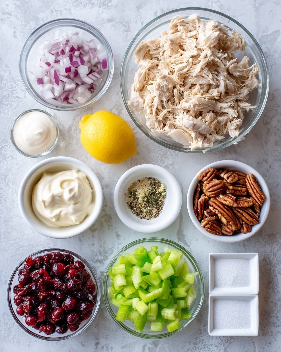 A clear glass bowl filled with shredded light brown chicken sits at the top center of the image. Below it are three small white bowls; the left bowl holds white sour cream with a smooth texture, the middle bowl contains creamy white mayonnaise that looks thick, and the right bowl is filled with brown pecans, showing some shine on their textured surfaces. To the right of the pecans is a yellow lemon, while below it is a small white bowl filled with a mix of green garlic salt, black pepper, and light green celery seed. In the center below the mayonnaise is a small white bowl of dark red cranberries with a shiny and slightly wrinkled texture. To the left, a clear bowl contains finely chopped purple and white onion pieces. A clear bowl below holds chopped bright green celery stalk pieces. Two small white square dishes at the bottom right contain white sugar and clear vinegar. The arrangement is on a white marbled surface. photo taken with an iphone --ar 4:5 --v 7