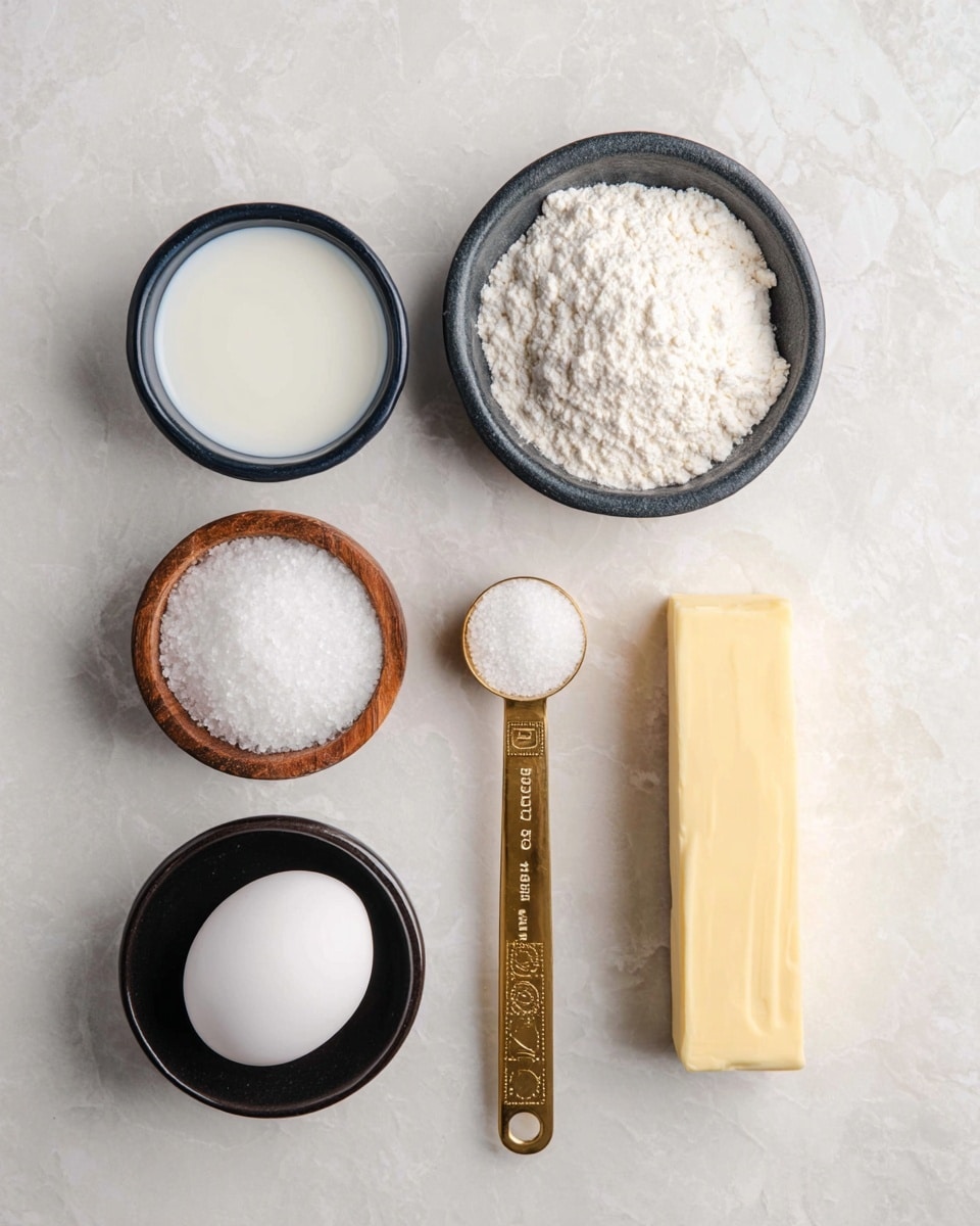 The image shows seven baking ingredients arranged neatly on a white marbled surface. Starting from the top center, there is a small black bowl filled with white flour, with a grainy texture. Below it slightly to the left, a gold measuring spoon holds fine light brown yeast. Beneath the spoon is a small round wooden bowl with white granulated salt. To the right of the yeast and salt, a single white egg is placed. Above the egg, on the right side, is a stick of yellow butter with blue measurement markings on the wrapper. Below the egg and a little right, there is a small black bowl filled with fine white sugar. Lastly, at the bottom left corner, a white scalloped bowl holds a small amount of white liquid milk. The items are evenly spaced, and the shot is clear and well-lit. Photo taken with an iphone --ar 4:5 --v 7