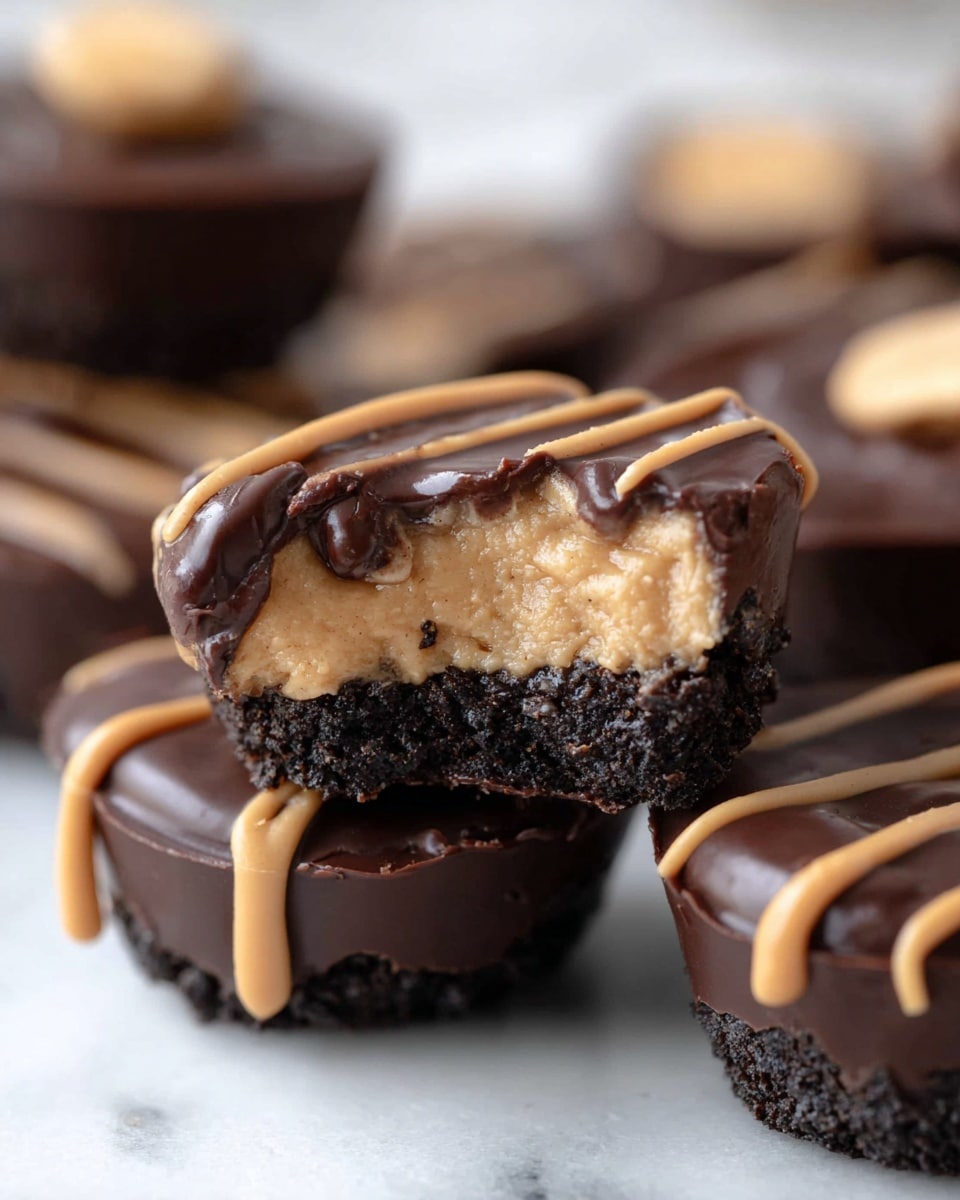 The image shows a close-up of dark chocolate cups filled with a light tan peanut butter center. Each cup has three clear layers: the bottom and sides are a rough dark chocolate shell, the middle is a smooth, creamy peanut butter filling, and the top is a shiny dark chocolate layer. Some cups have light tan peanut butter drizzle on top, while one cup in the background has a round peanut butter piece on top. The cups are placed on a white marbled surface, and a woman's hand is gently holding one cup with the peanut butter filling visible. photo taken with an iphone --ar 4:5 --v 7