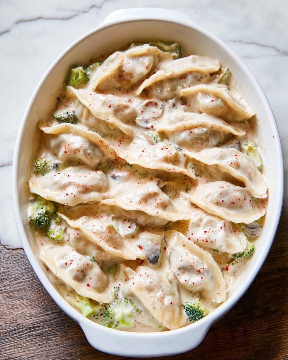A white oval dish filled with two layers; the bottom layer has small pieces of green broccoli and white mushrooms, partially visible through a creamy white sauce with tiny red specks. On top, there are two rows of pale dumplings with a soft texture, slightly overlapping and covered in the same creamy sauce with small red dots. The dish is set on a white marbled surface. Photo taken with an iphone --ar 4:5 --v 7