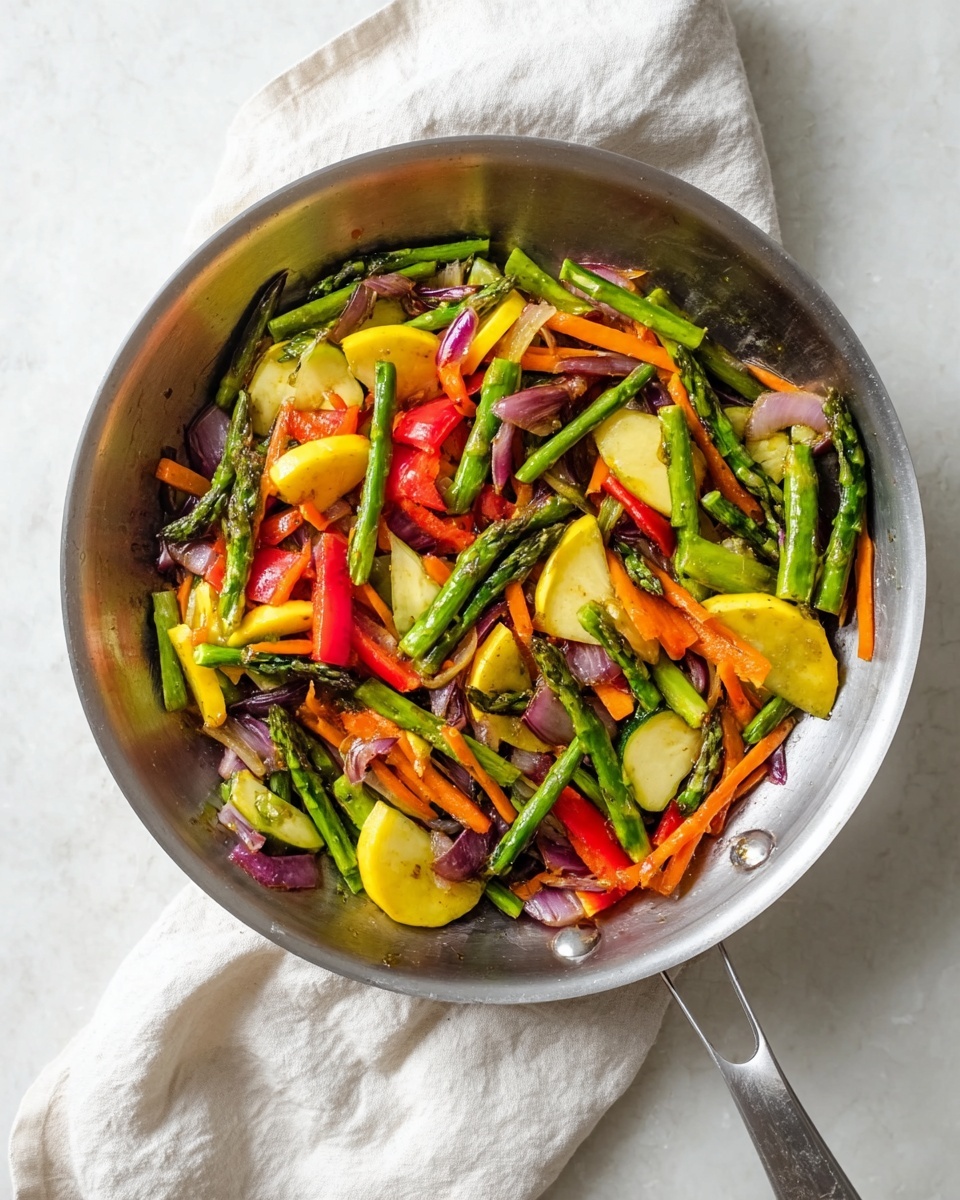 A metal pan filled with a colorful mix of vegetables including green asparagus spears, bright red bell pepper strips, pale yellow half-moon slices of squash, thin carrot sticks, and pieces of purple onion, all lightly cooked and mixed together. The pan rests on a soft white cloth on a white marbled surface. The vegetables show fresh, slightly cooked textures with vibrant colors contrasting against the shiny metal pan. photo taken with an iphone --ar 4:5 --v 7